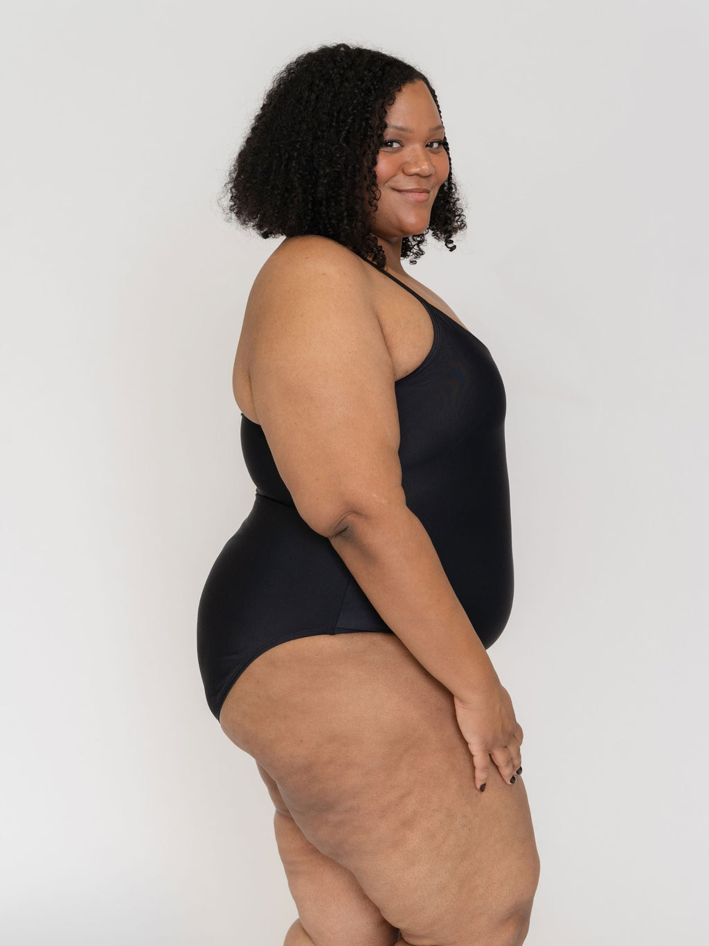 Woman wearing a black one piece swimsuit against a white background