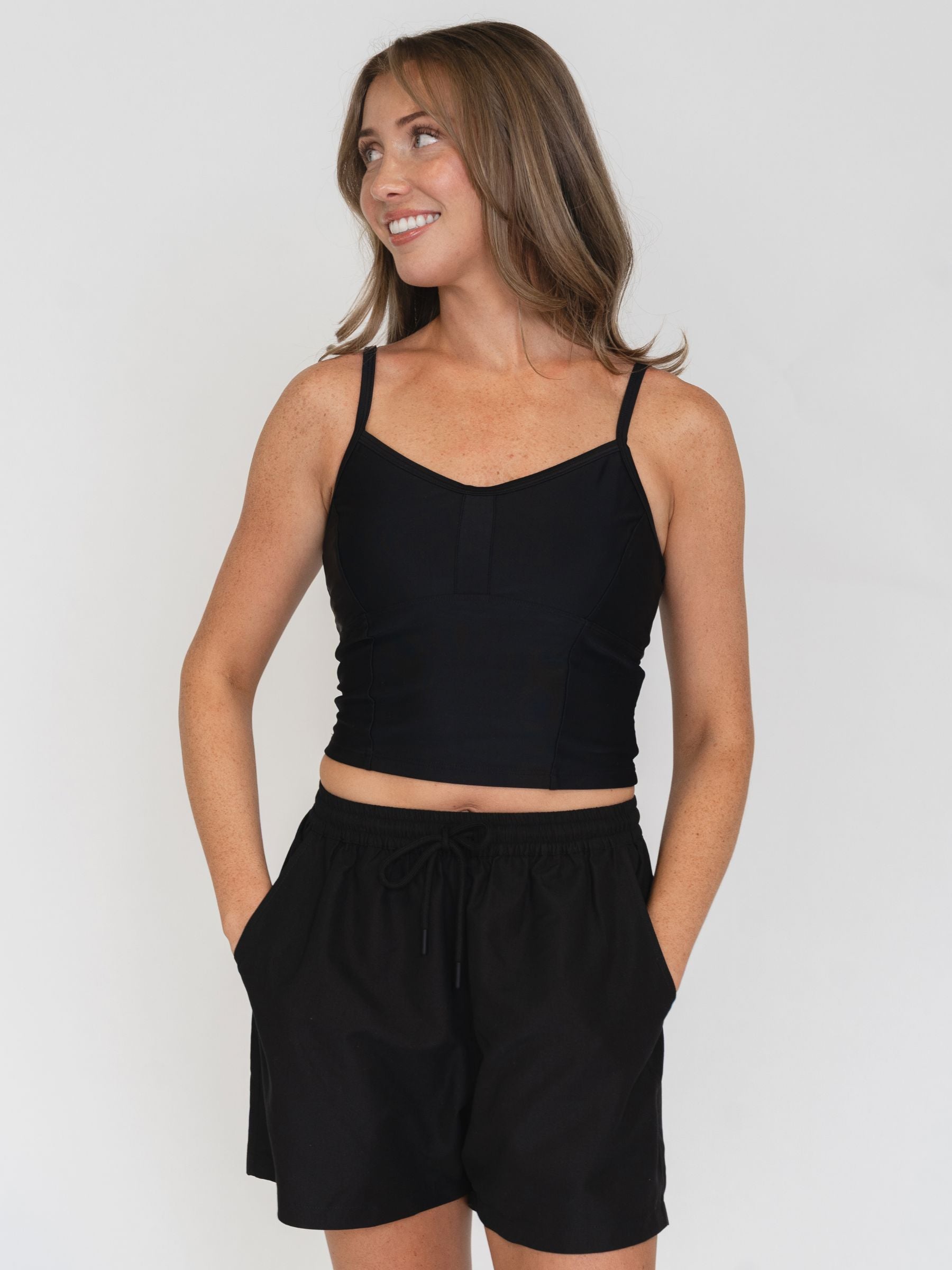 Woman wearing a black tank top and black shorts on a white background
