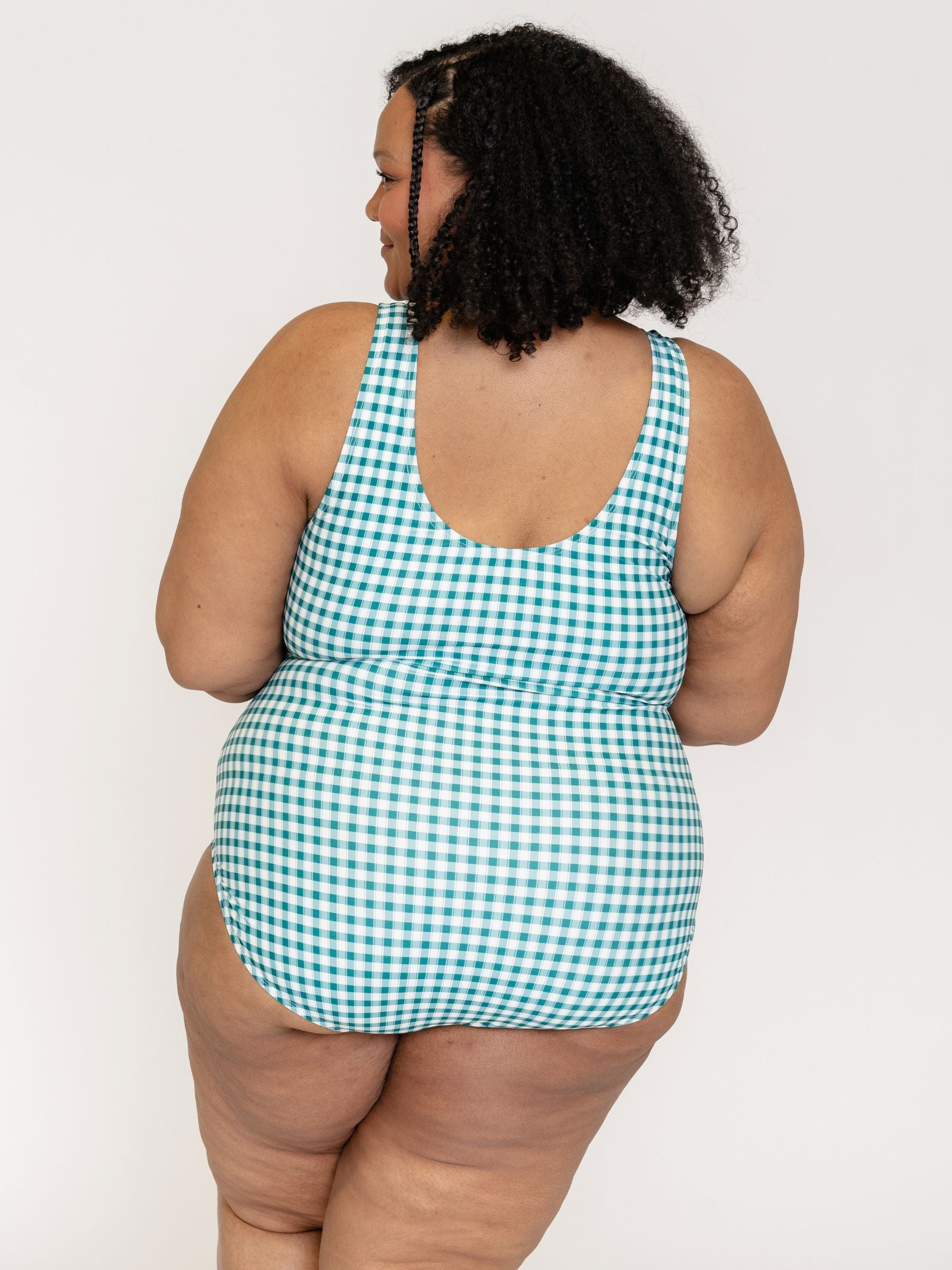 Woman  wearing a green and white checkered swimsuit against a plain background