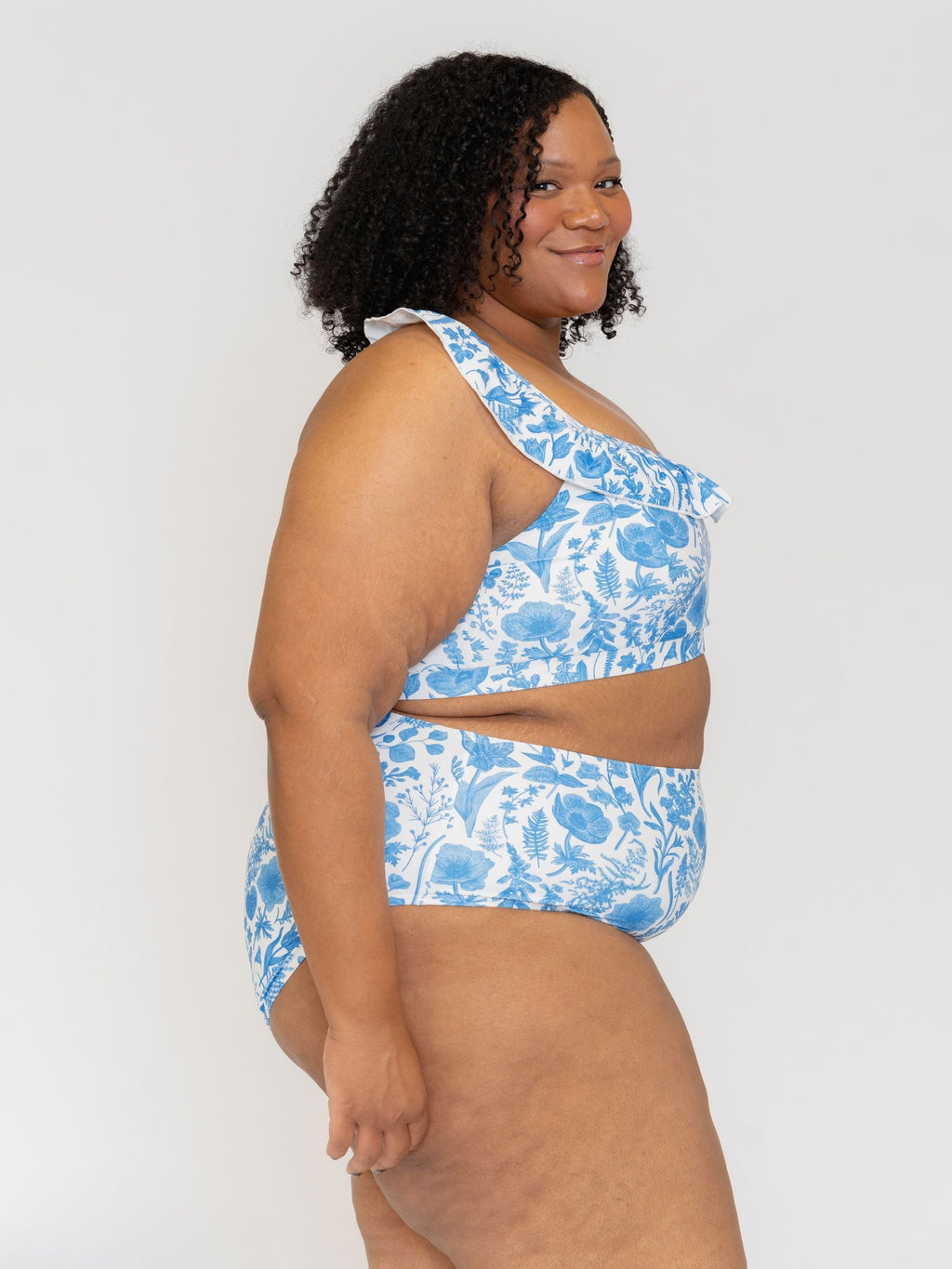 Side View of a Woman wearing a blue floral  swimsuit against a white background