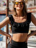 Woman wearing a black ruffled top and matching bottoms outdoors