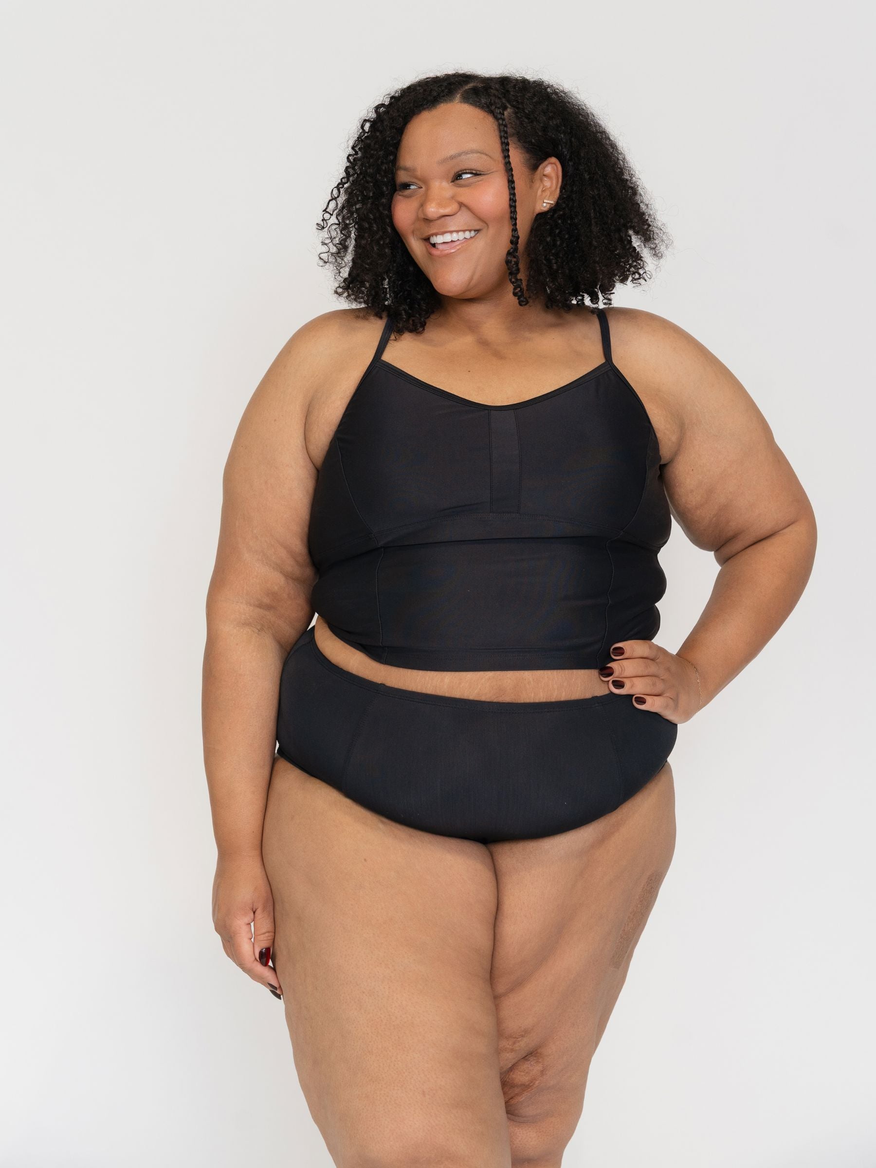 Woman wearing a black two-piece tankini swimsuit against a white background