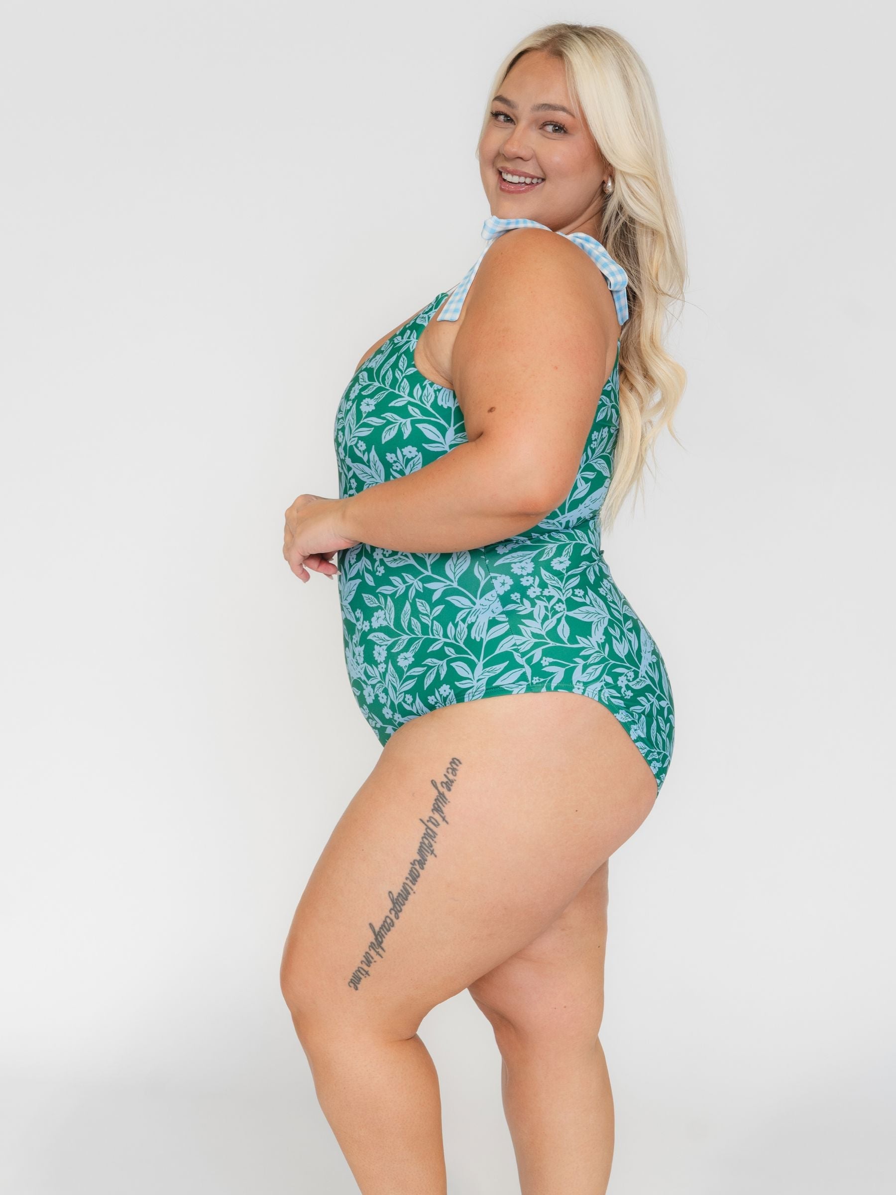 Woman wearing a white leaf-patterned one- piece swimsuit on a white background