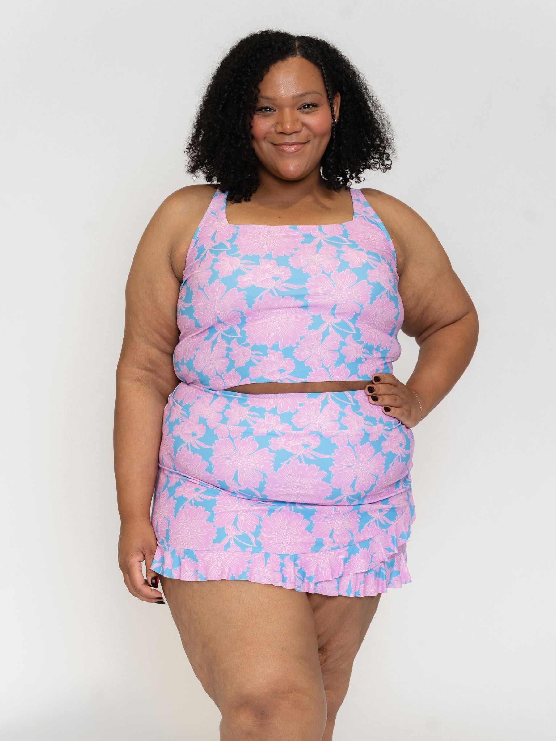 Woman wearing a pink and blue patterned swim set outfit on a white background
