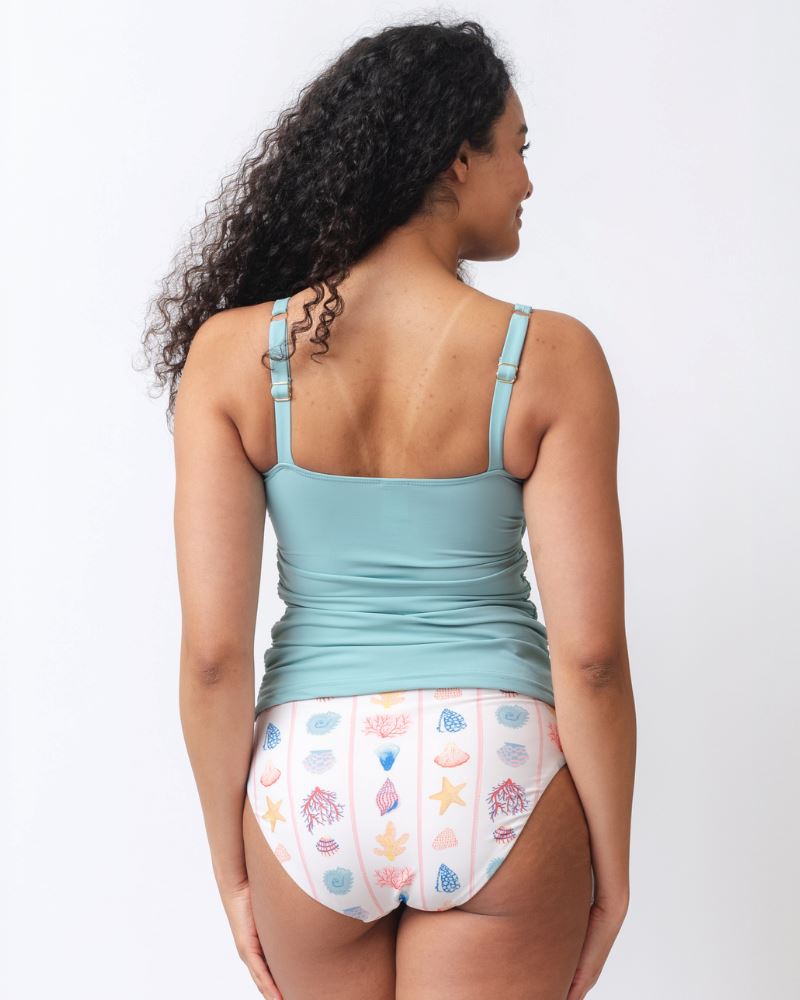 Photo of a woman wearing a seashell striped high waist swim bottom and a slight blue square neck swim tankini top- back angle