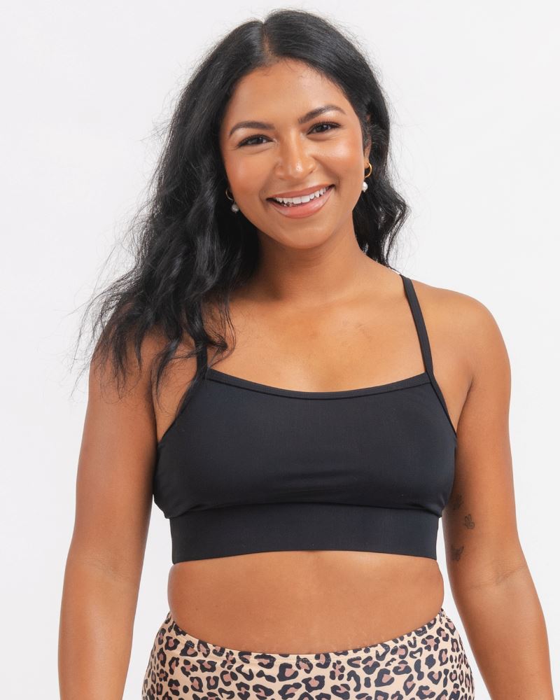 close up of a Woman wearing a black sports bra and leopard print bikini bottoms on a white background 