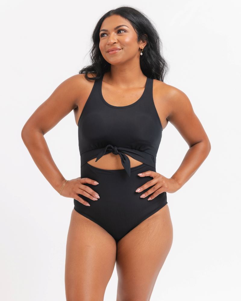 Woman wearing a black knotted one piece swimsuit with a white background
