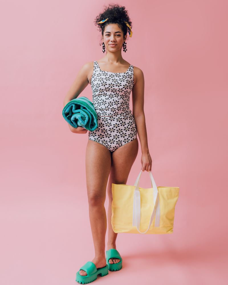 Photo of a woman wearing a green and blue floral/ white and black floral reversible swim bottom (white and black floral side) and a white and black swim top