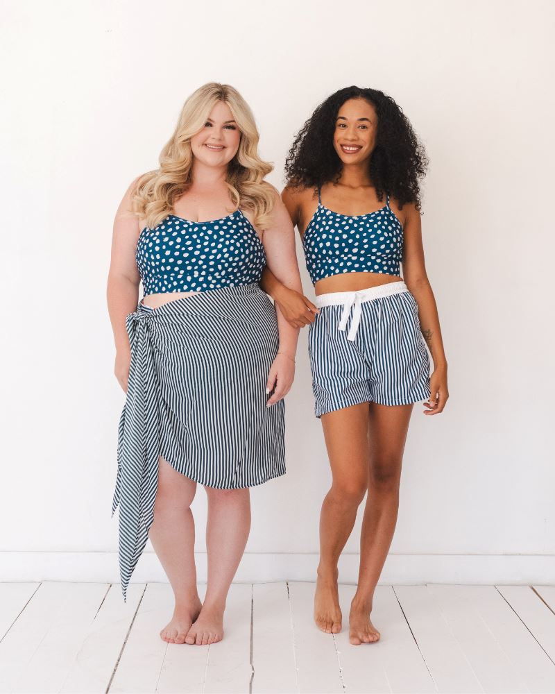 Photo of two women wearing a blue and white stripe Sarong and a blue and white dotted swim bralette and a blue and white stripe swim board short