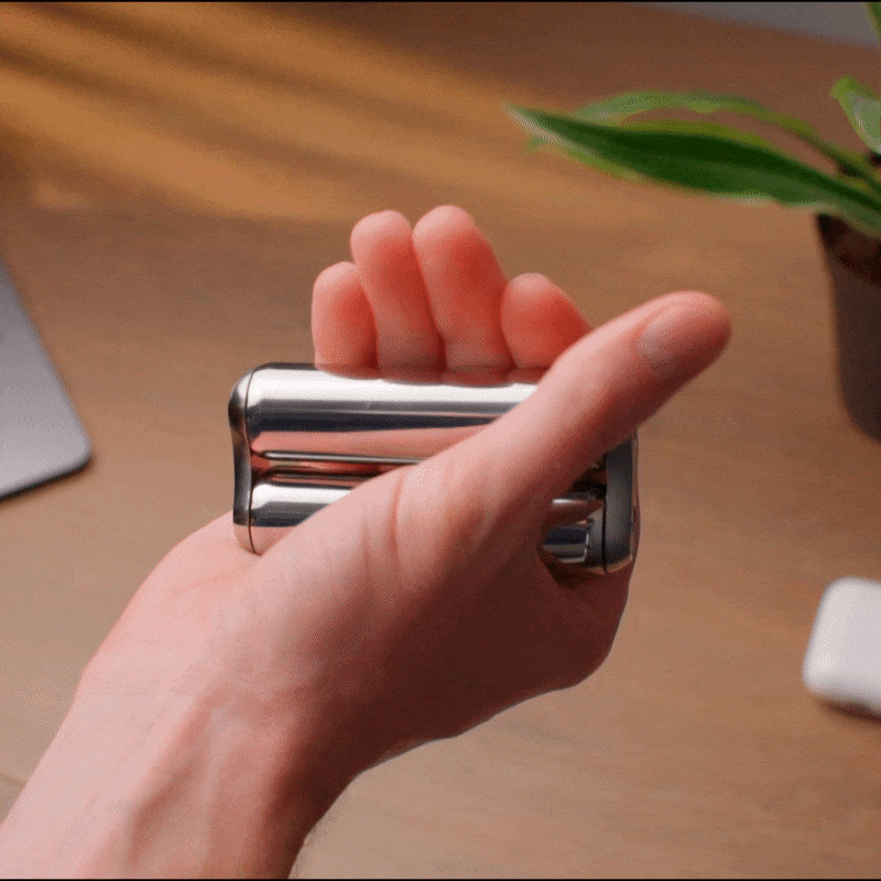 eam_Junior | Hand holding ONO Roller Steel heavy weighted fidget toy on desk