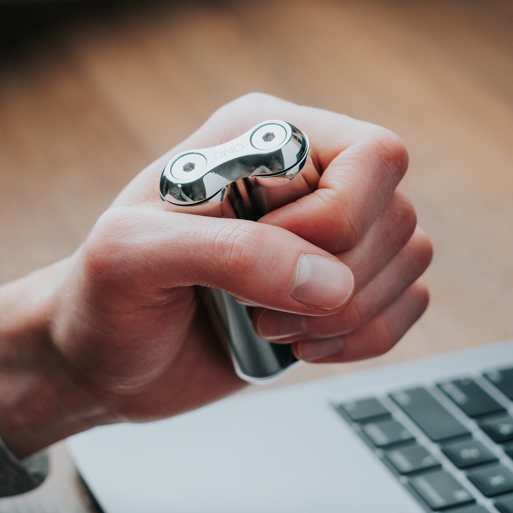 eam_Full | Hand holding ONO Roller Steel heavy weighted fidget toy near laptop keyboard