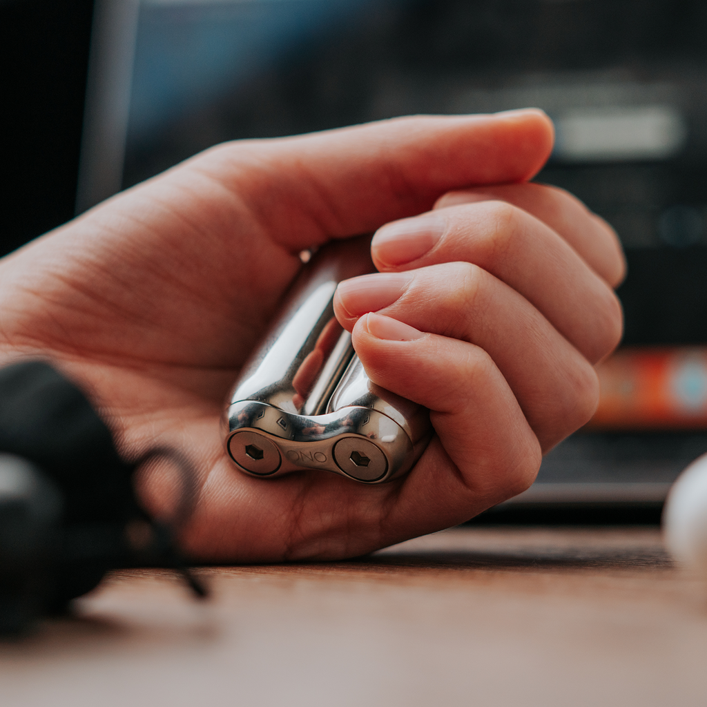 eam_Junior | Child's hand holding ONO Roller Steel fidget toy in silver finish