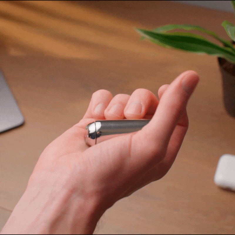eam_Mini | Hand holding ONO Roller Steel heavy weighted fidget toy on wooden desk