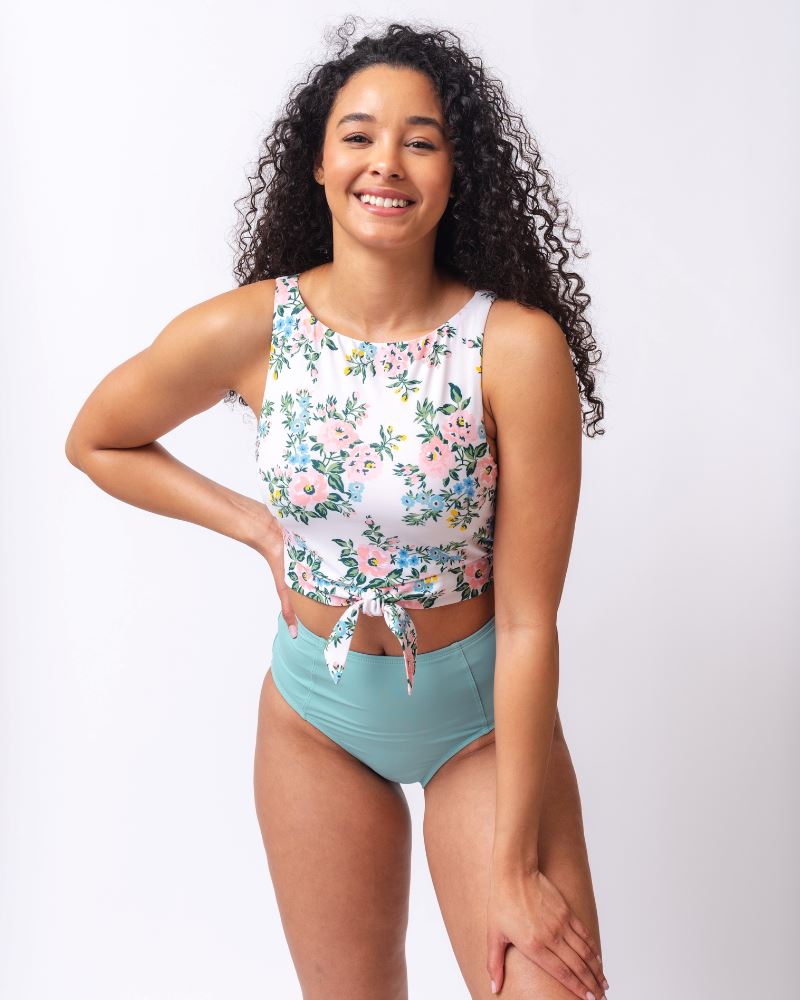 Photo of a woman wearing a pink and white floral cropped swim top with light blue high waist swim bottoms